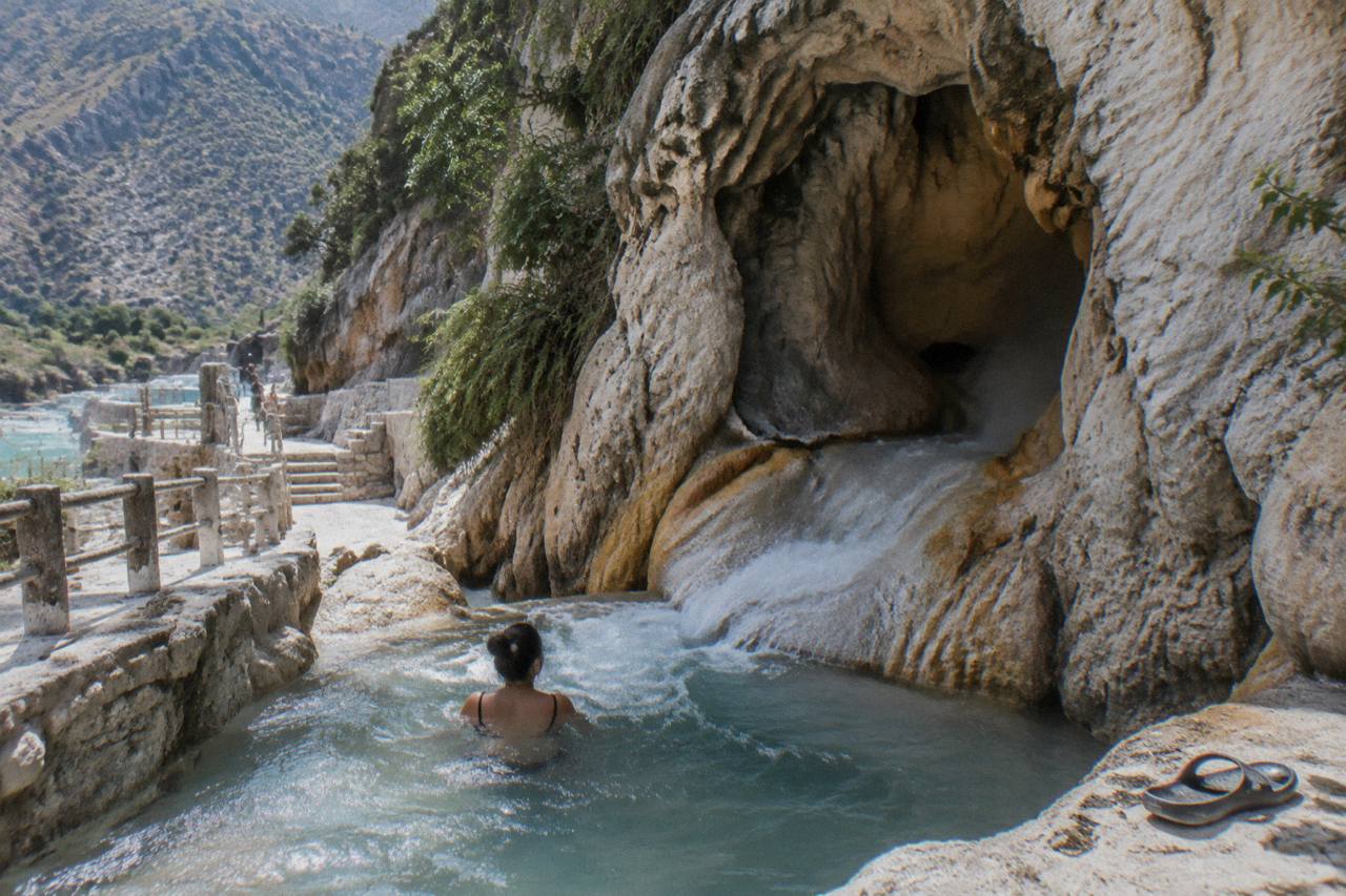 Warm water flowing from a cave mouth into a rocky channel inside the canyon