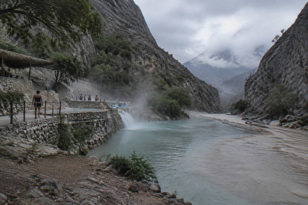 A shallow warm river bending between canyon walls with steam rising off the surface