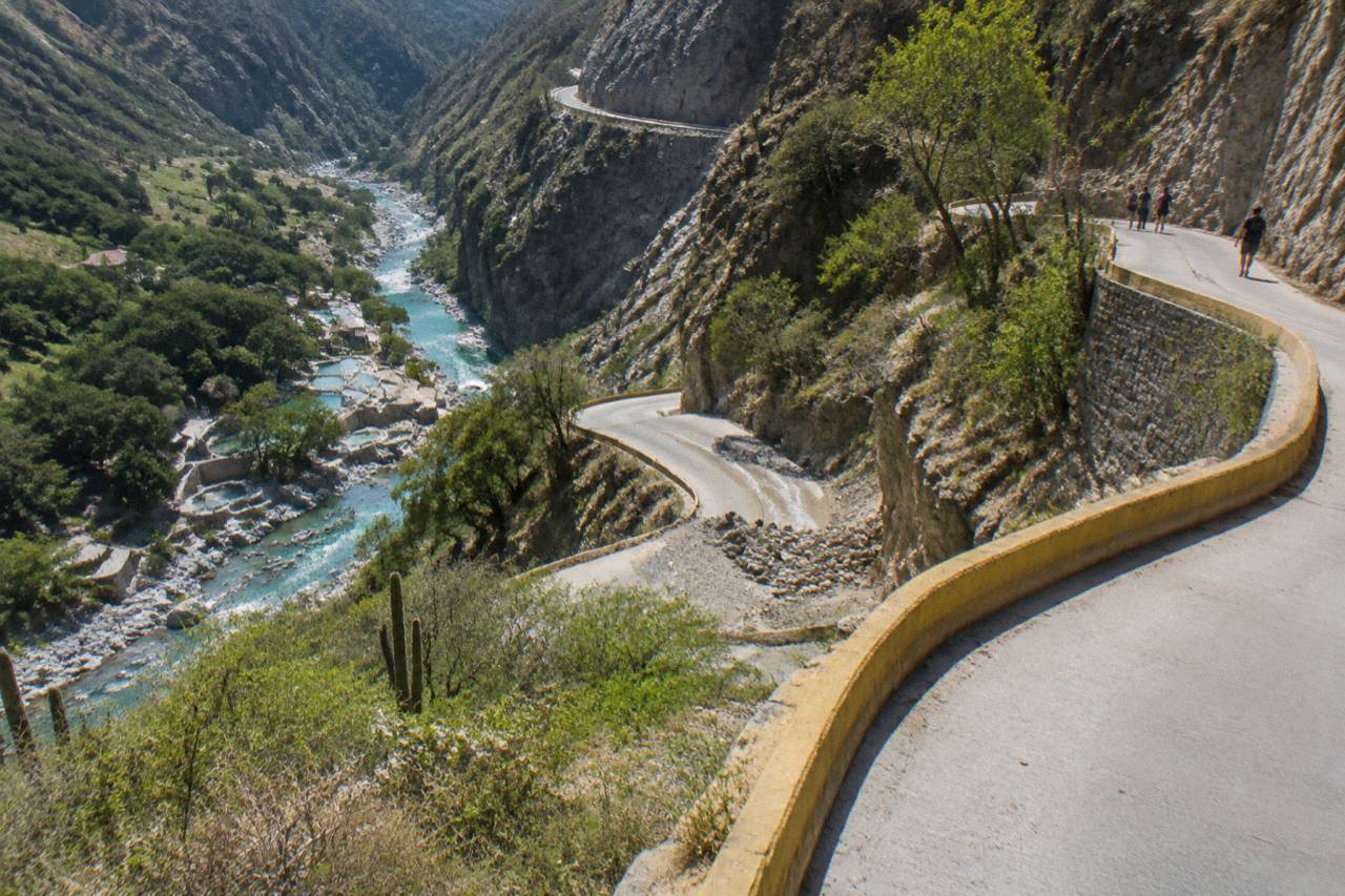 Steep paved canyon road with tight curves and rock walls above the Tolantongo river gorge.