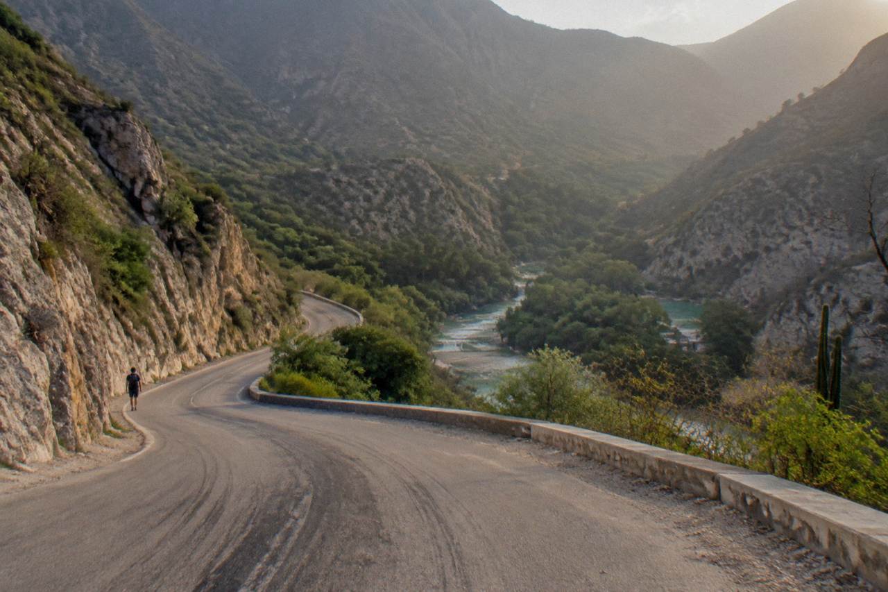Winding paved mountain road descending toward the green Tolantongo canyon in Hidalgo, Mexico.
