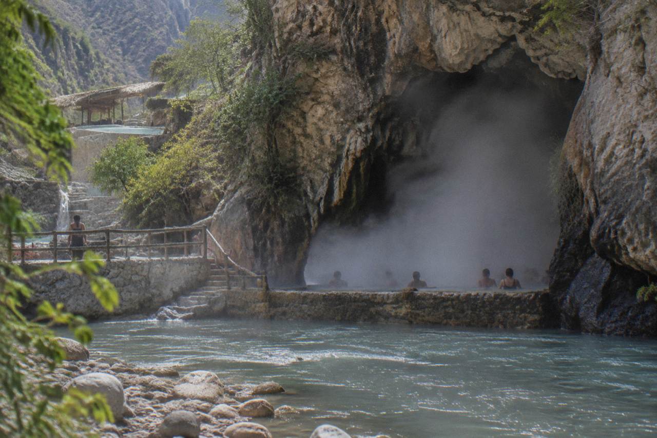 Steam rising from the mouth of a thermal cave opening onto the river