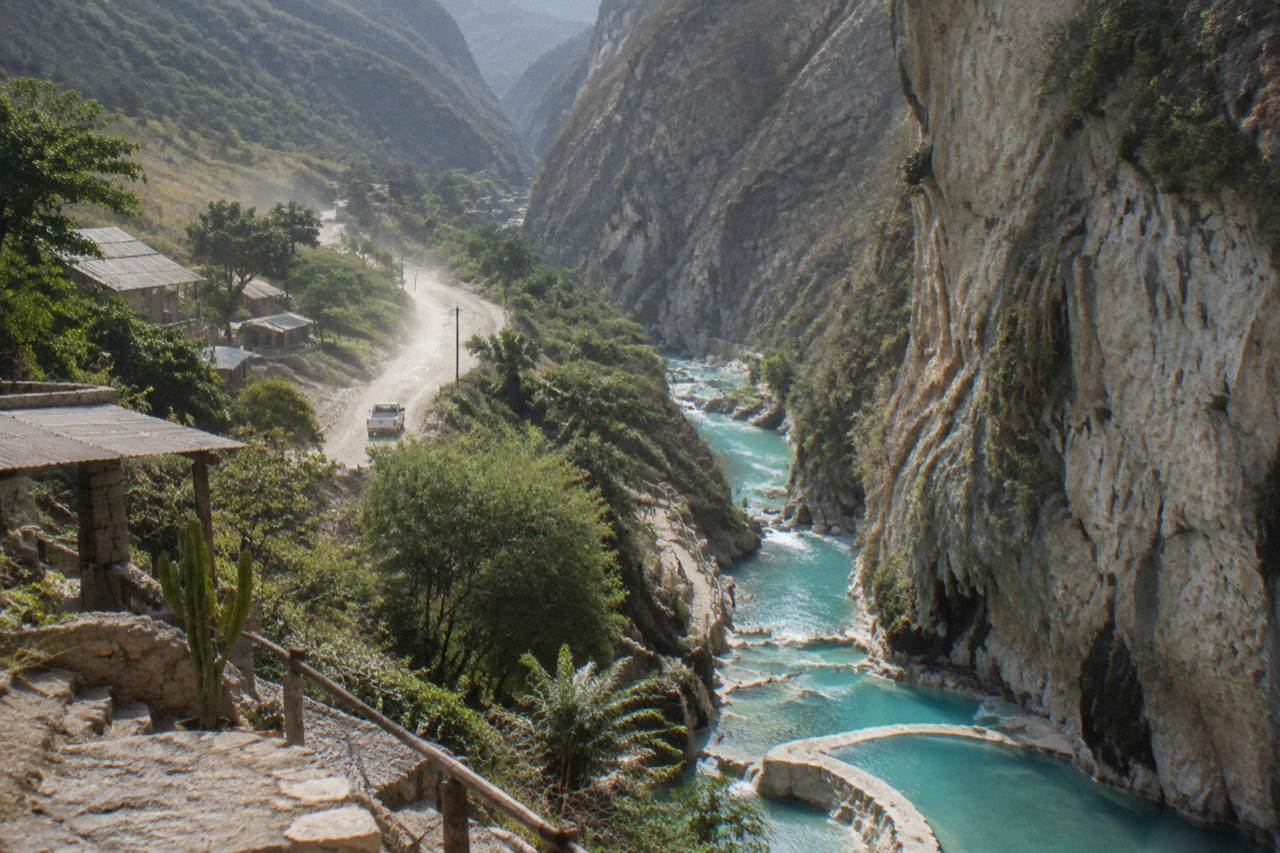 Steep canyon walls above a turquoise thermal river winding through the Tolantongo valley