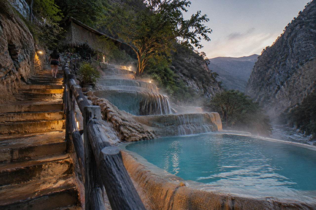 Thermal pools built into the canyon cliffside with warm water steaming in cool air