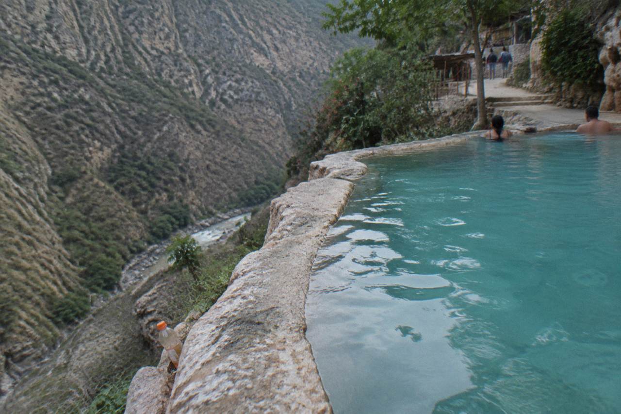A private thermal pool tucked into the cliffside at Grutas de Tolantongo, with canyon walls rising behind turquoise water