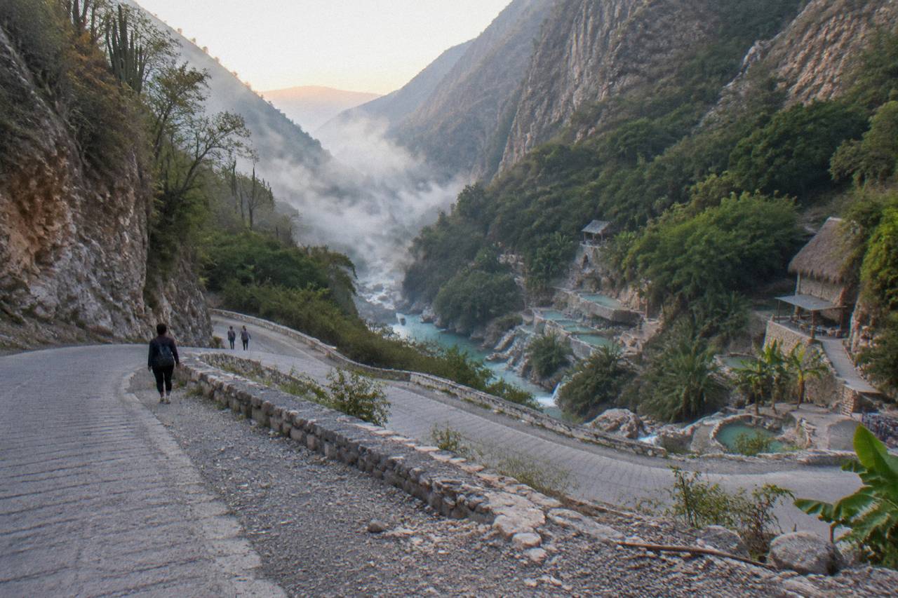 A shuttle road winding down the canyon side toward the thermal river at Grutas de Tolantongo