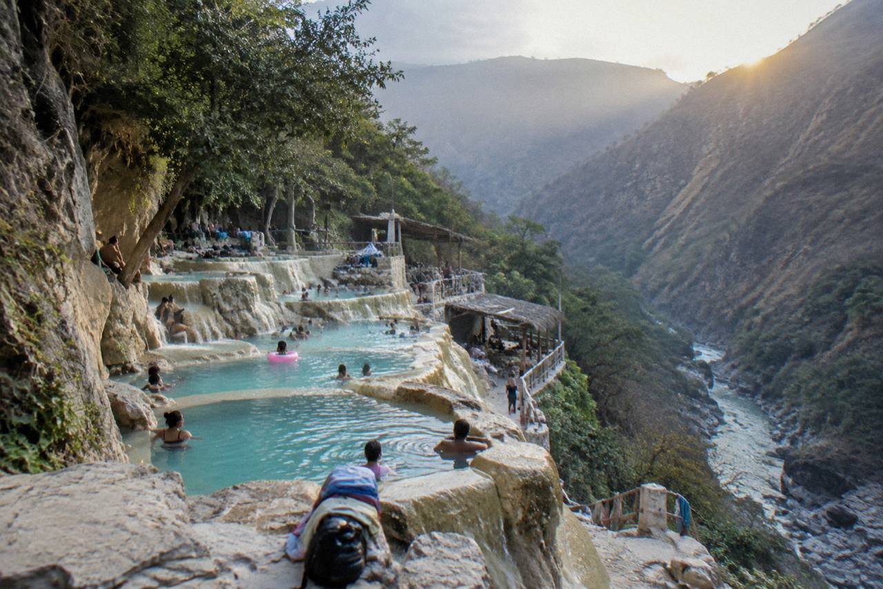 Stepped thermal pools built into a canyon slope with morning light on the water
