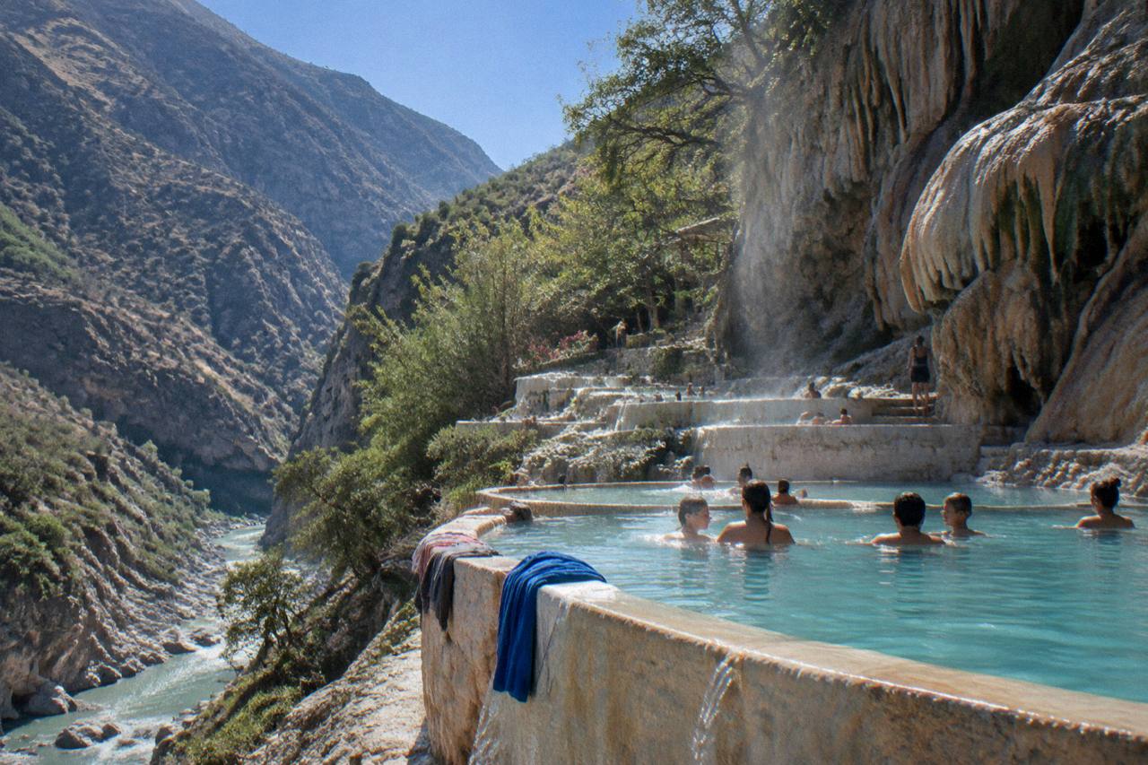 Warm thermal pools on a canyon ledge under a clear blue sky
