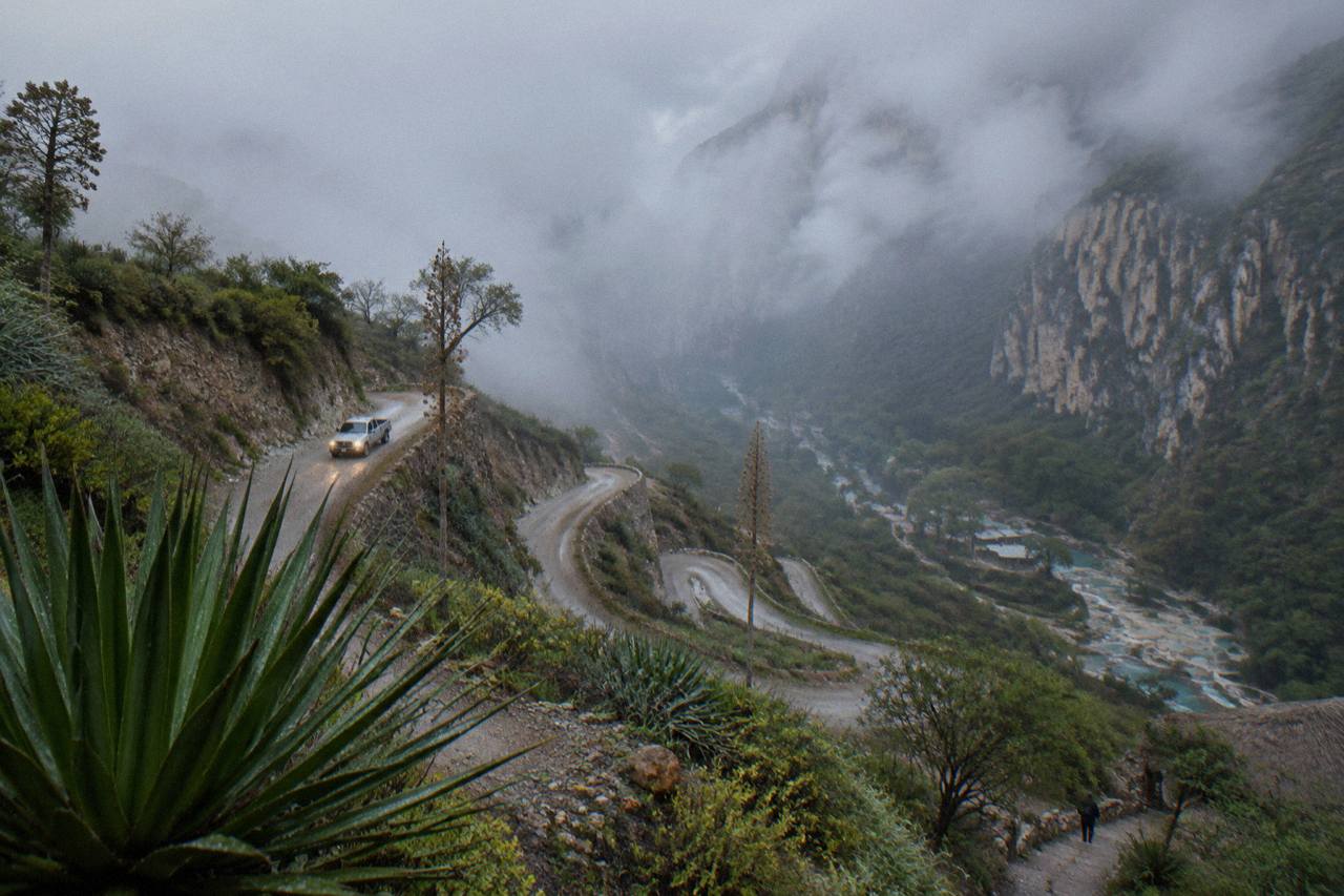 Winding mountain road descending toward the Tolantongo canyon with cliffs on both sides