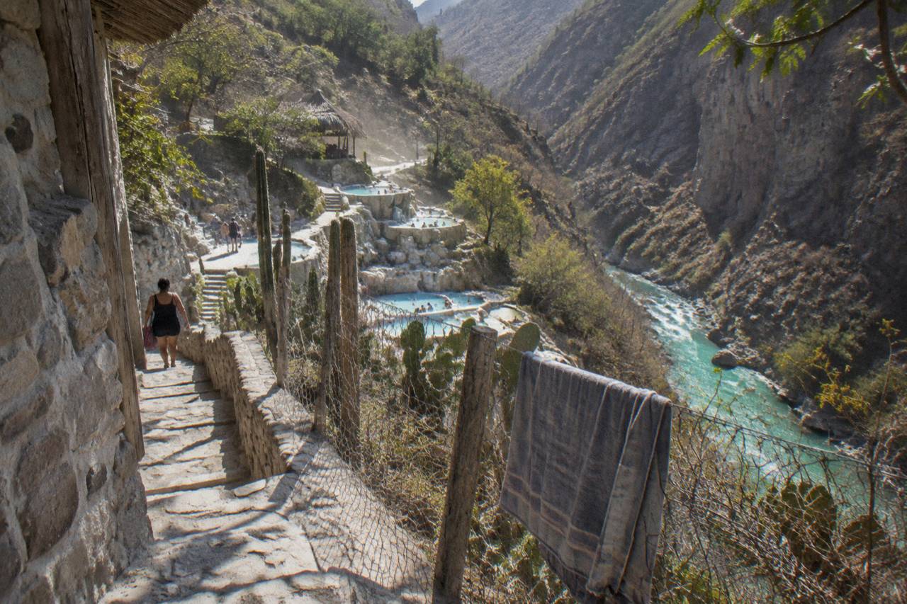 Thermal pools and the river seen from a cliffside path above the canyon