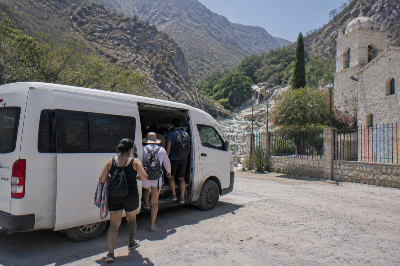 Regional bus parked at a mountain town terminal with passengers boarding