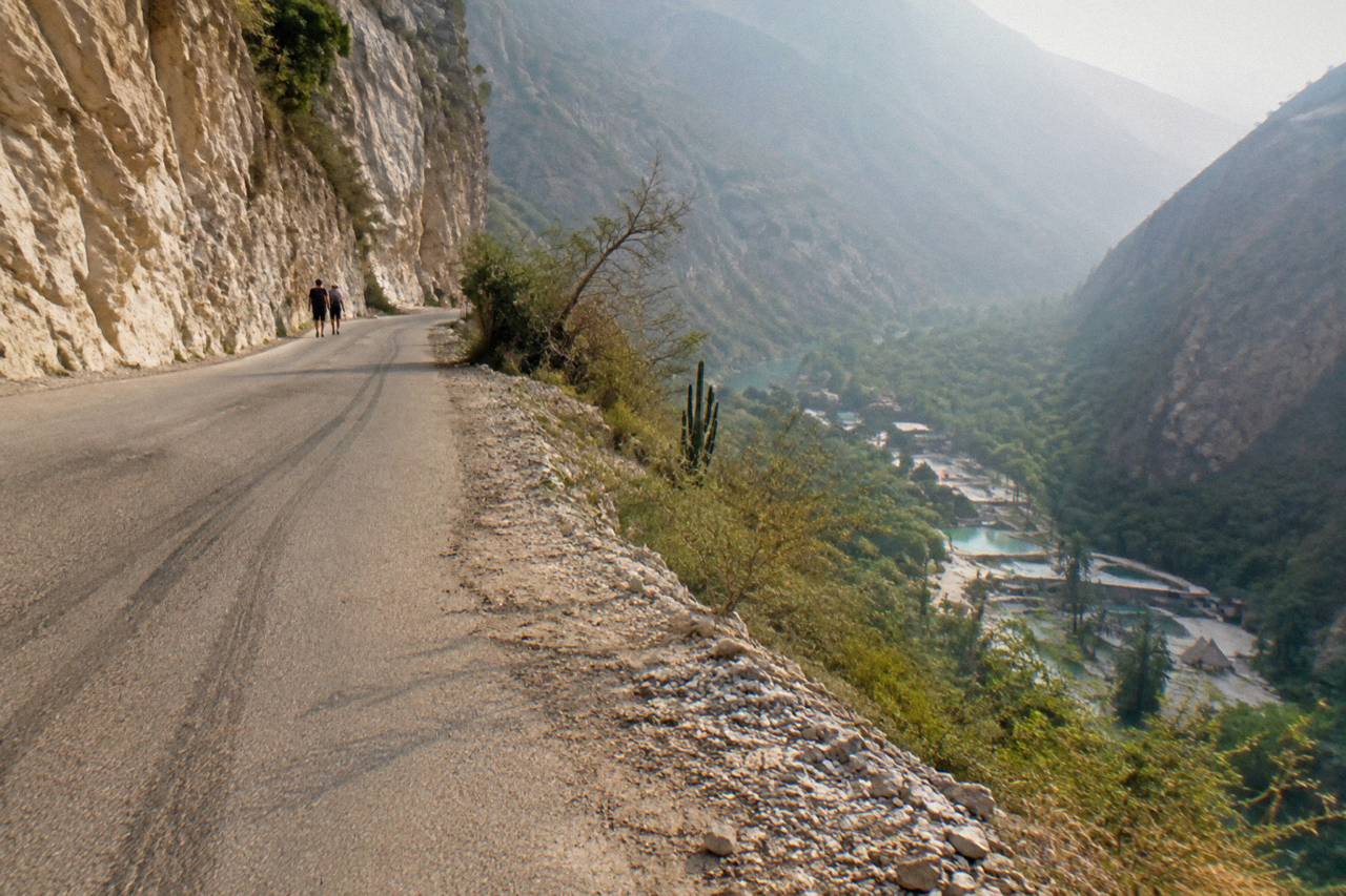 Steep curving canyon road with rock walls on one side and a deep valley on the other