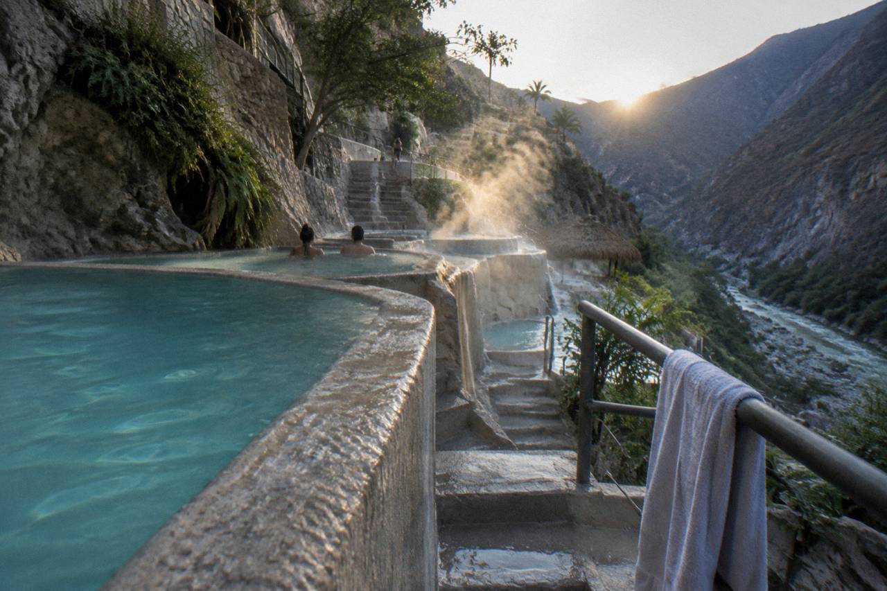Steam rising from thermal pools built into a cliffside overlooking the canyon