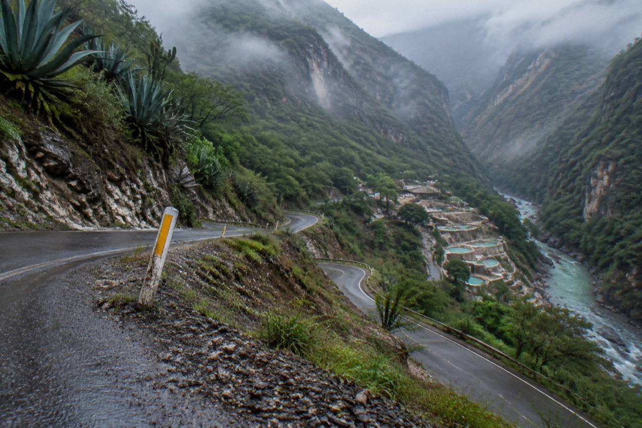 Winding mountain road descending toward a deep canyon with green walls