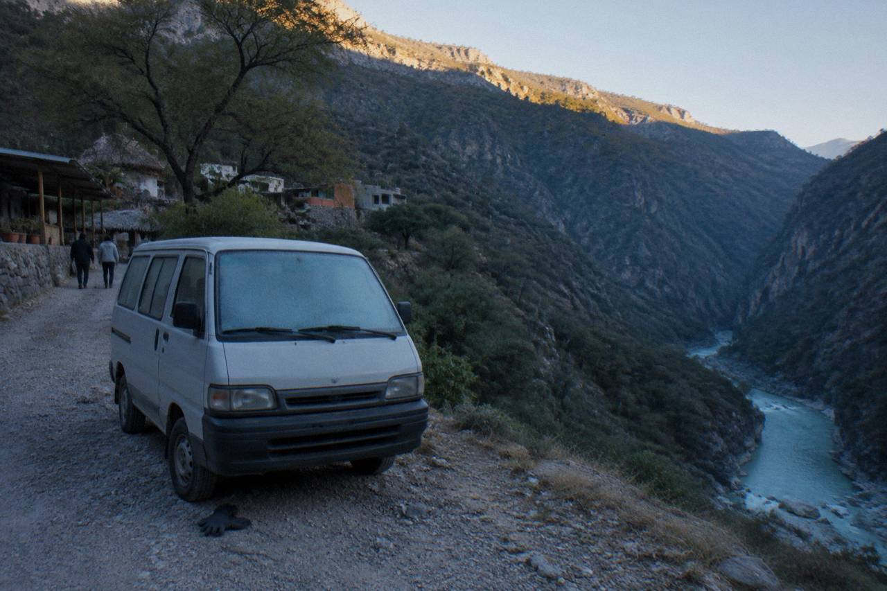 Small van parked on a mountain road shoulder above a river canyon