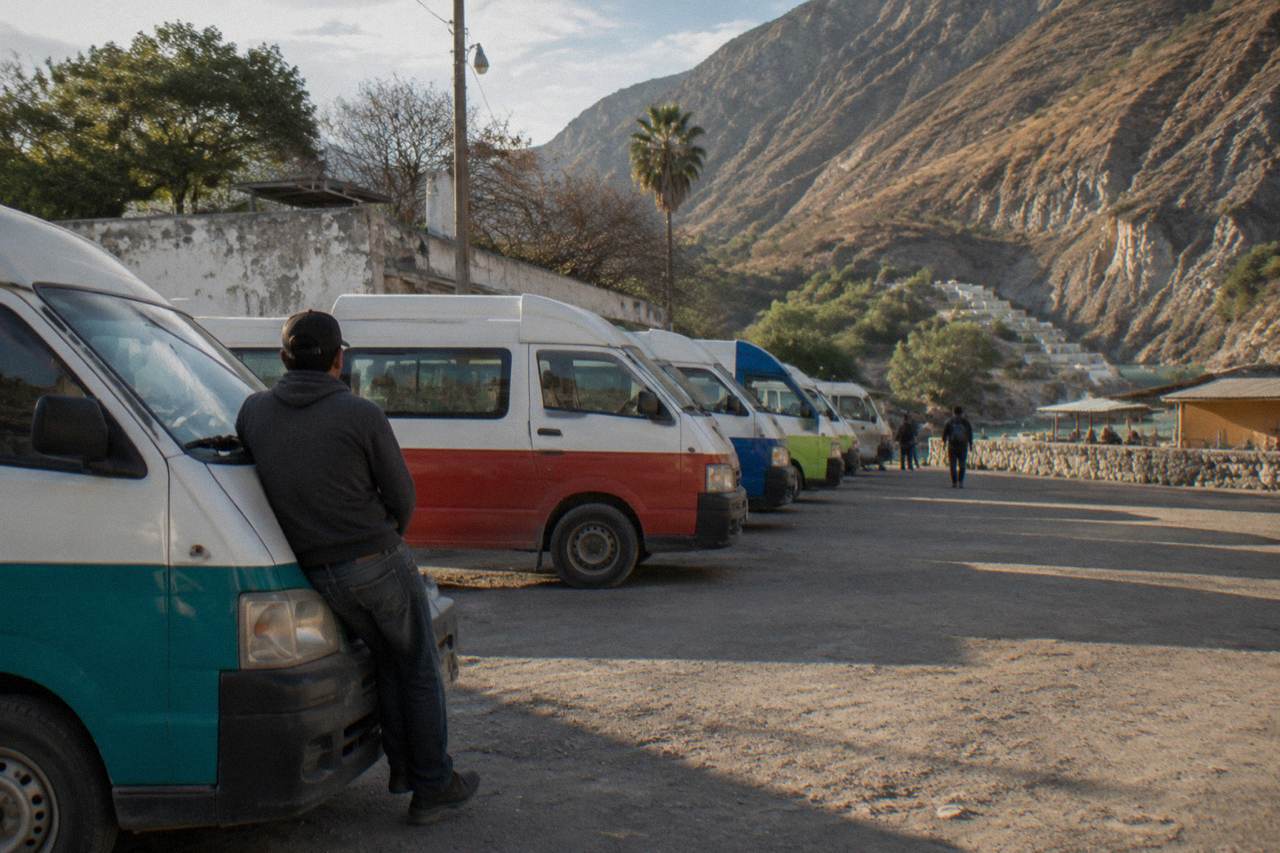 Row of colourful combi vans parked at a roadside shuttle stop in a Mexican town