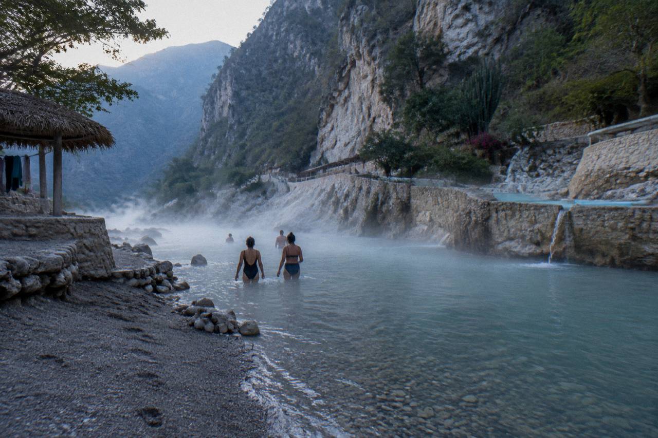 A shallow warm river flowing between canyon walls with bathers at the edge