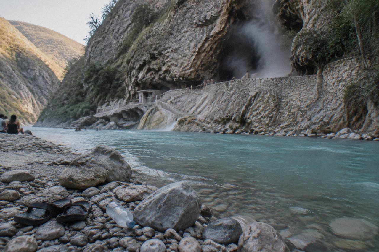 Steam rising from the thermal cave opening in the canyon wall in early morning light