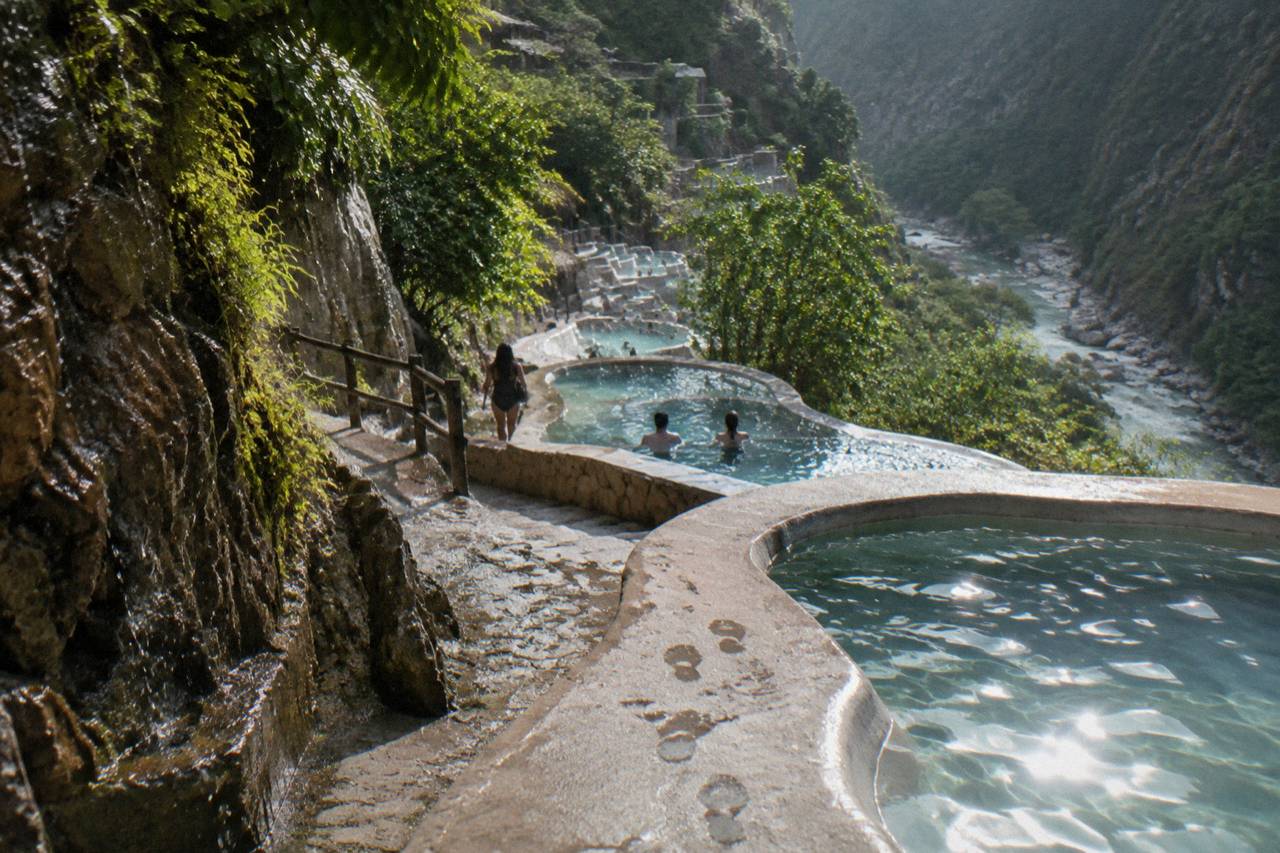 Rows of terraced thermal pools on the canyon cliffside in mid-morning sun