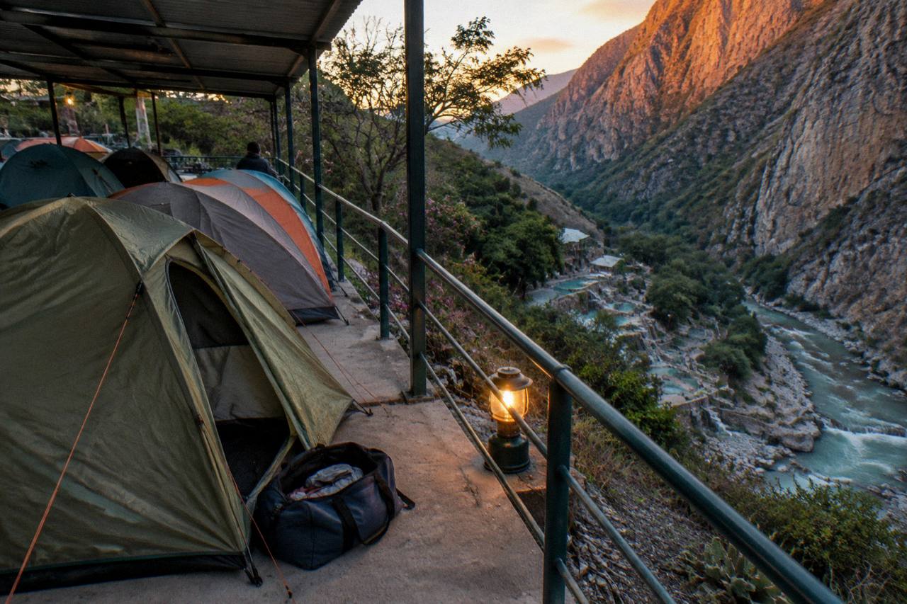 Camping tents pitched on a terrace above the canyon with evening light on the cliffs