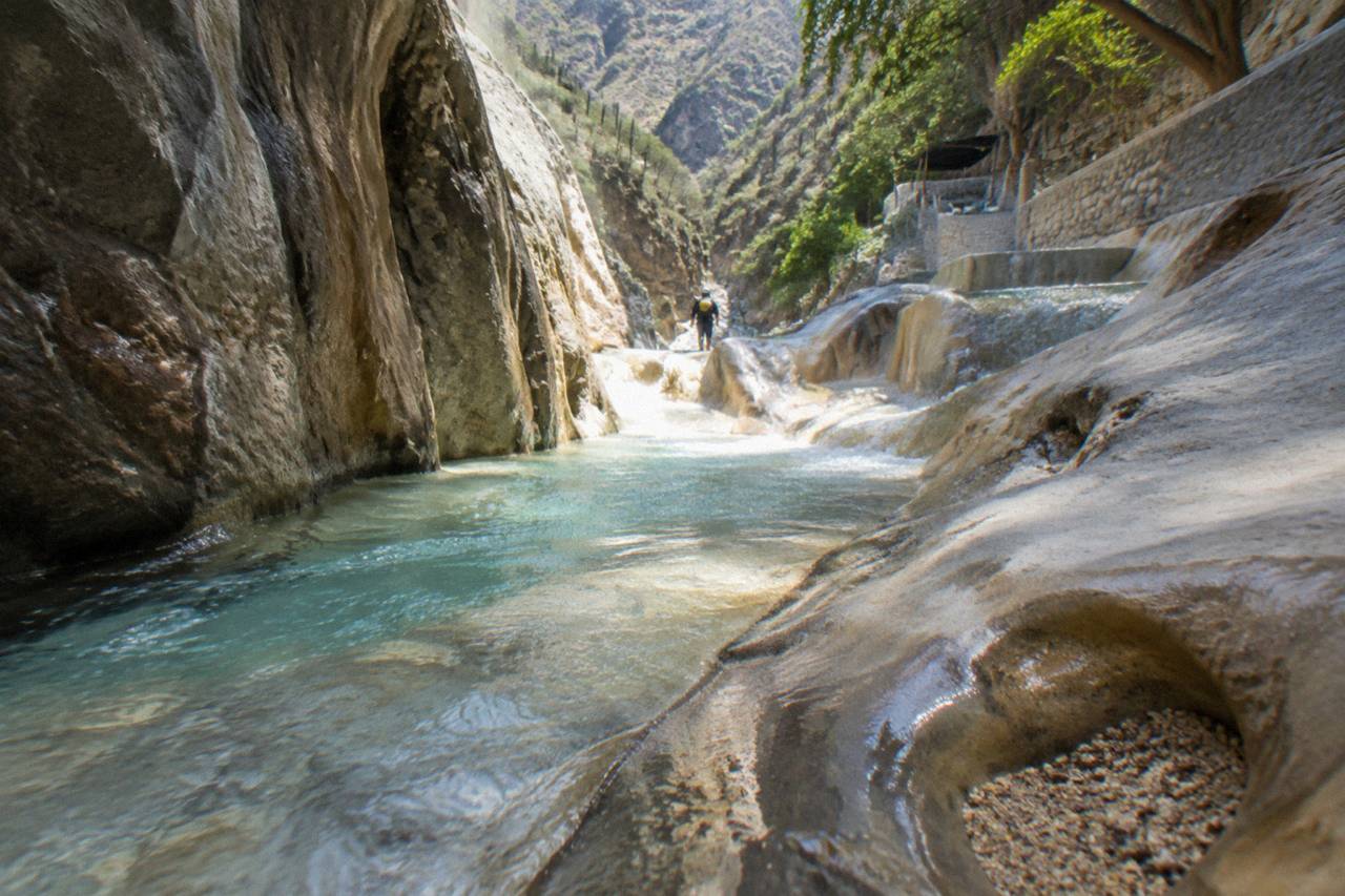 A narrow canyon with warm water and smooth rock walls in morning light