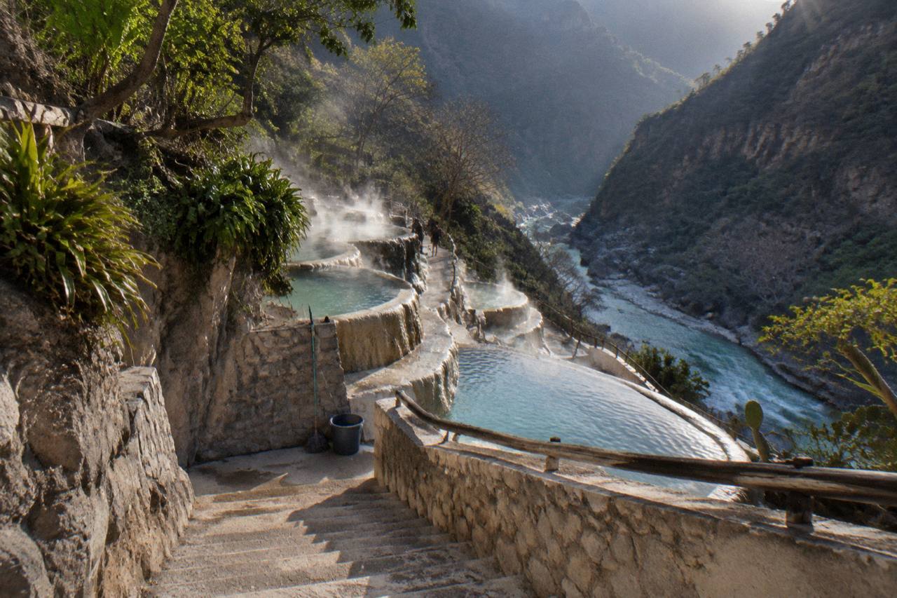 Steam rising off warm pools in early morning light in an empty canyon