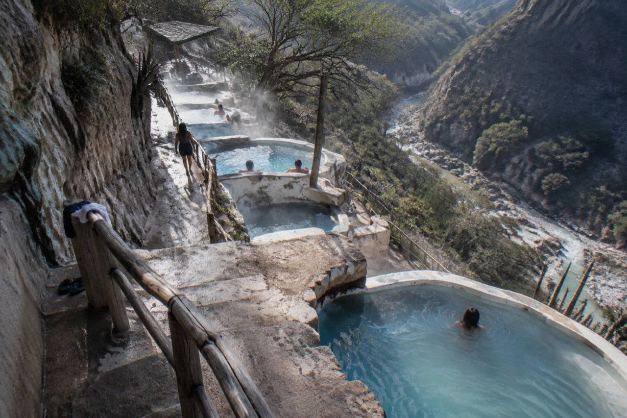 A row of natural thermal pools built into the cliffside overlooking the canyon