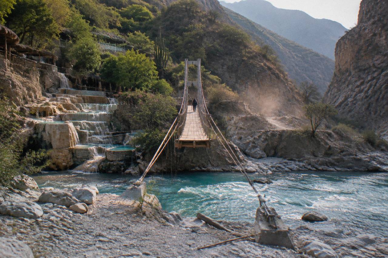 A narrow hanging bridge crossing above the thermal river in the canyon