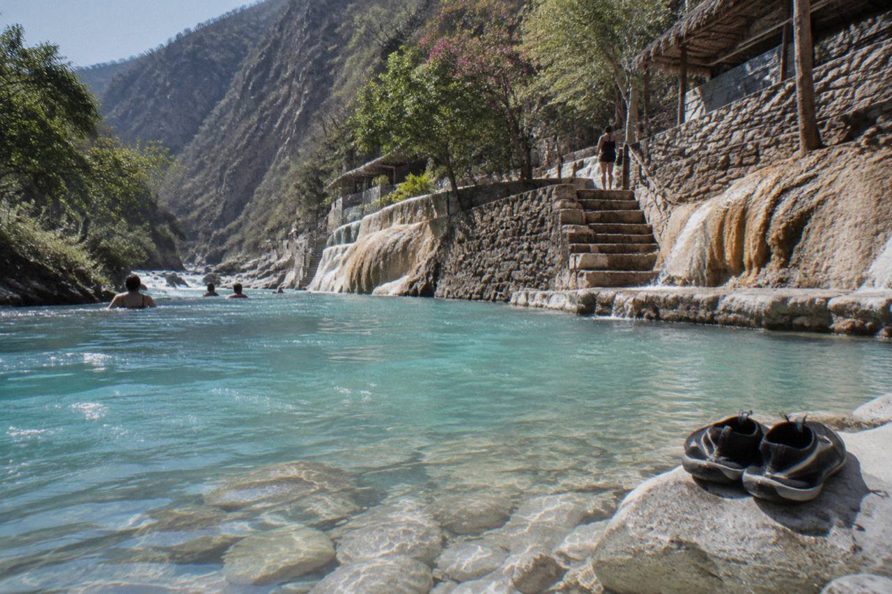 Turquoise thermal river flowing between steep canyon walls at Tolantongo