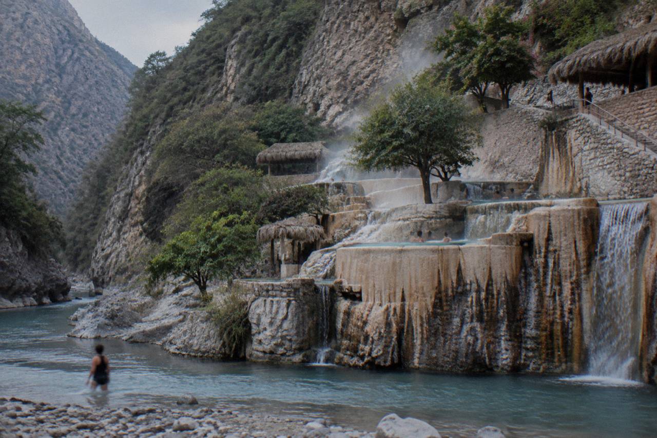 Terraced warm pools on a canyon wall above a narrow river bend