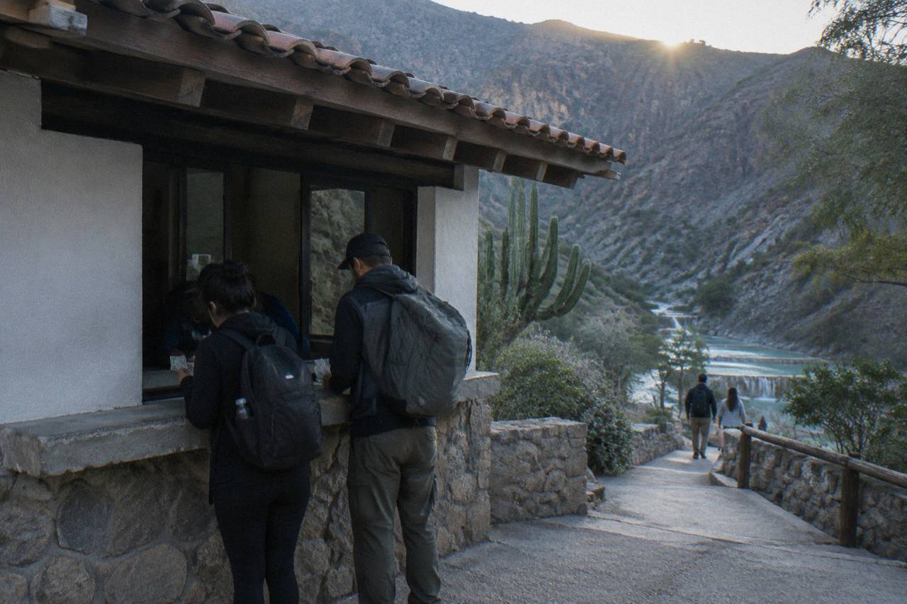 Travelers counting Mexican peso bills at a small ticket window