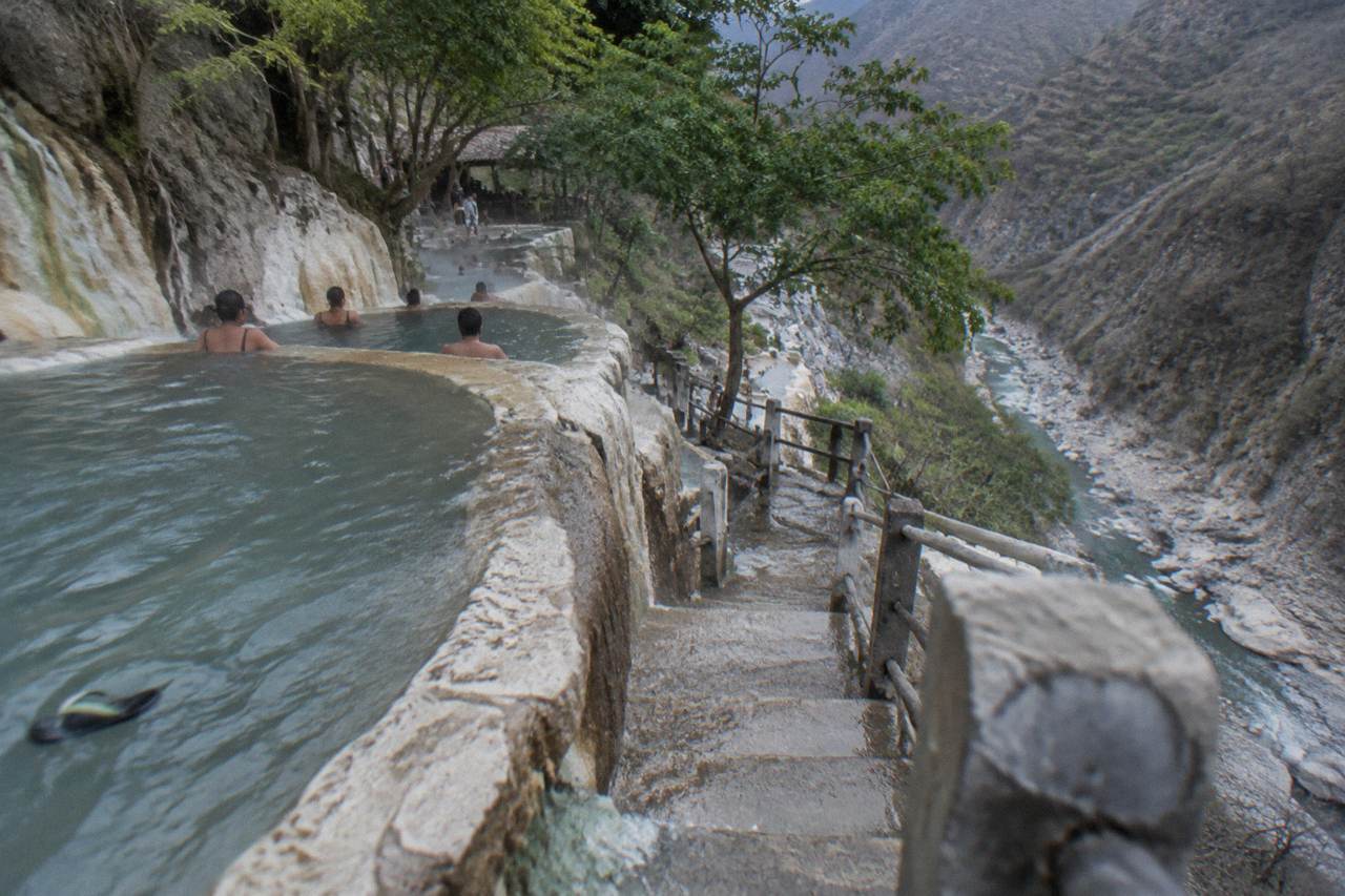 Crowded cliffside thermal pools carved into the canyon wall