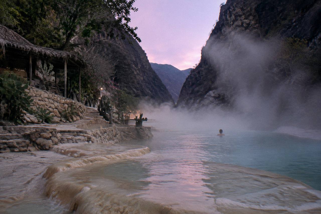 Steam rising from the warm thermal river between canyon walls at dusk