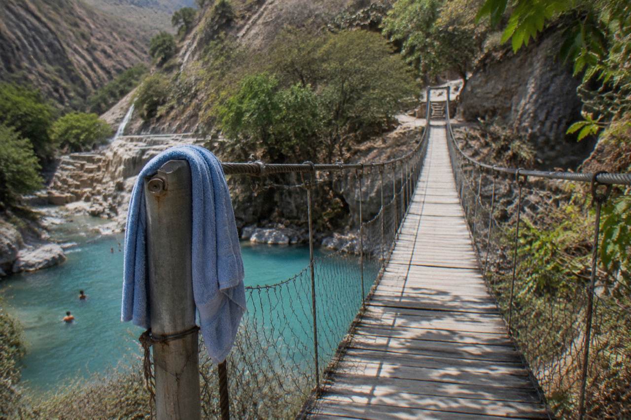 Narrow suspension bridge crossing above the thermal river between canyon walls