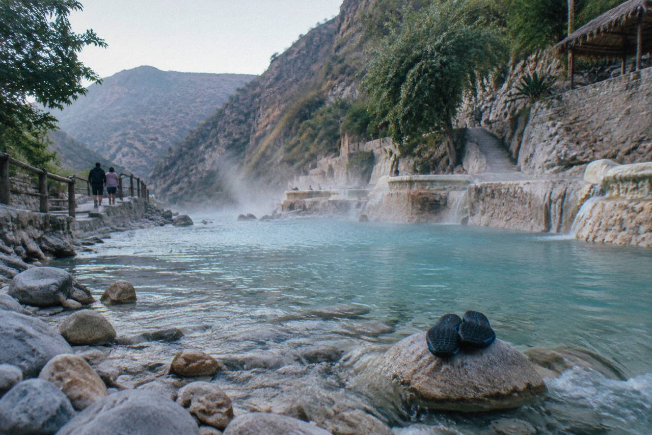 Shallow turquoise thermal river over smooth stones between canyon walls