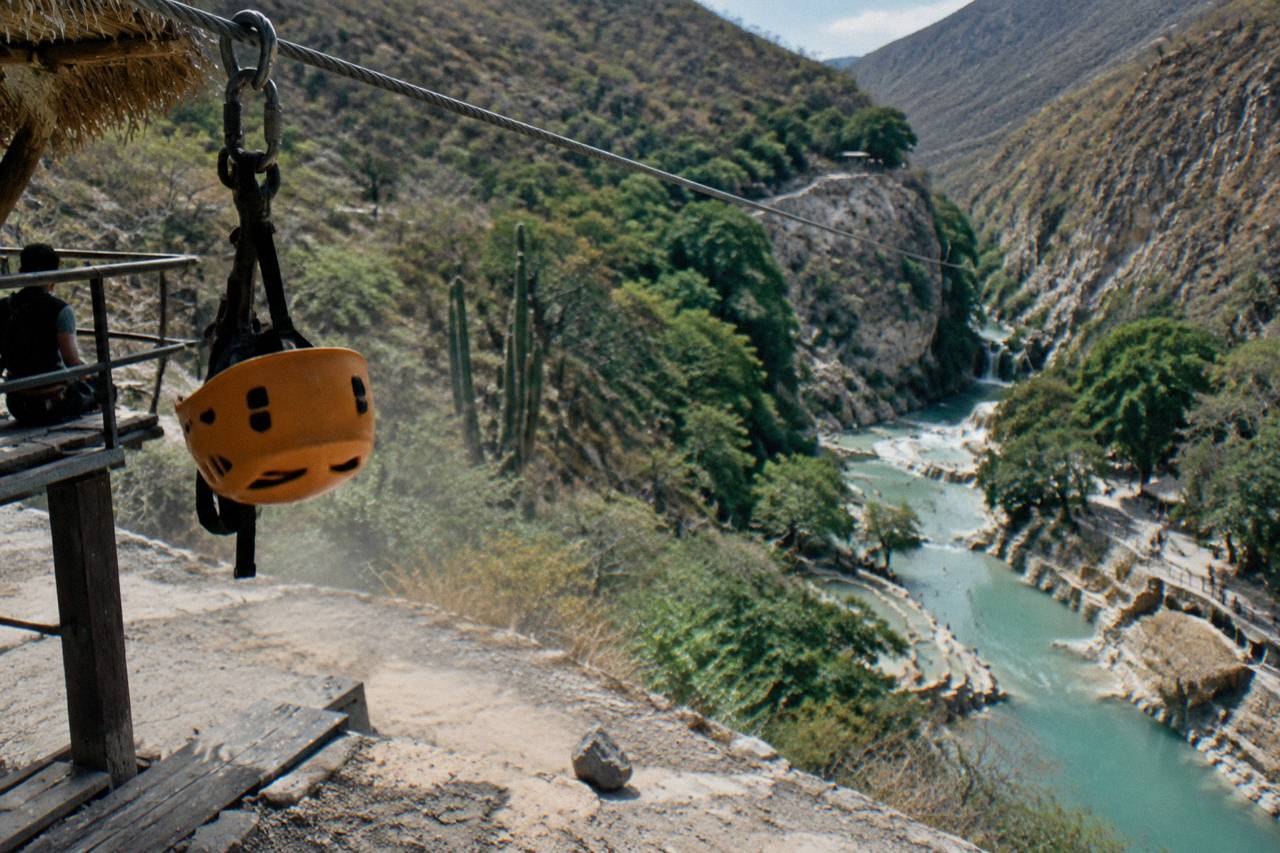 Long zipline cable stretching across the green canyon high above the thermal river